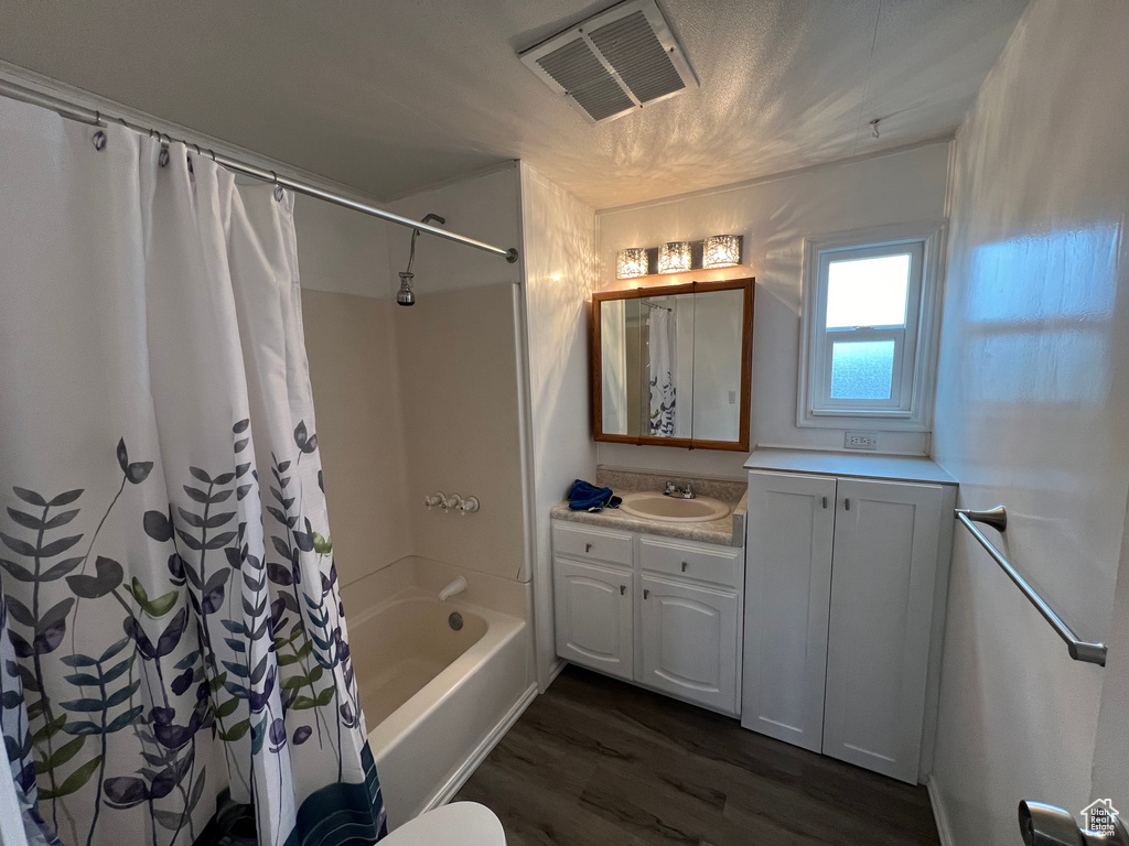 Full bathroom with shower / bath combo with shower curtain, toilet, large vanity, and wood-type flooring