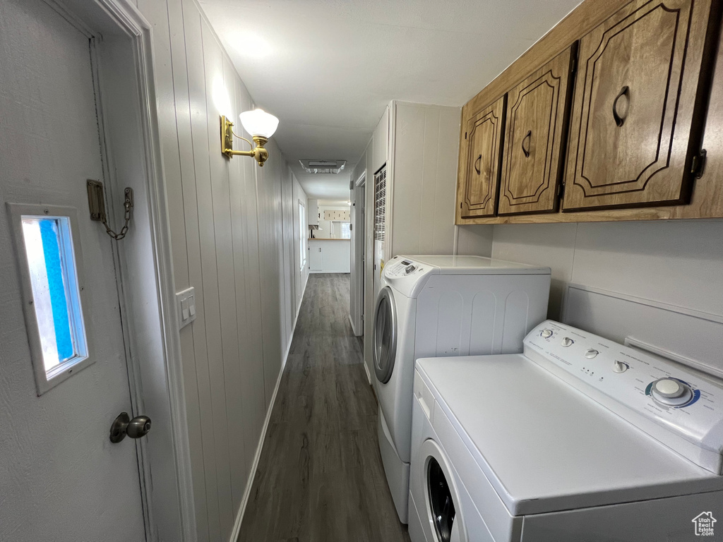 Clothes washing area with cabinets, dark wood-type flooring, and washing machine and clothes dryer