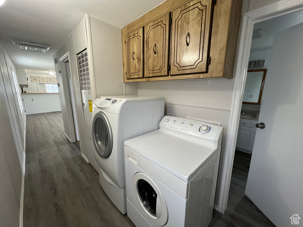 Laundry room with dark wood-type flooring, cabinets, and washing machine and dryer