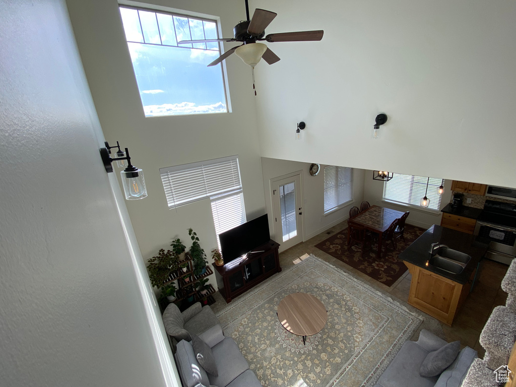 Living room with ceiling fan, sink, carpet flooring, and a high ceiling