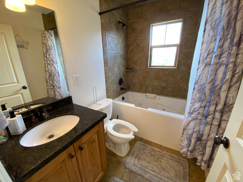 Full bathroom featuring shower / bath combination with curtain, toilet, vanity with extensive cabinet space, and tile flooring