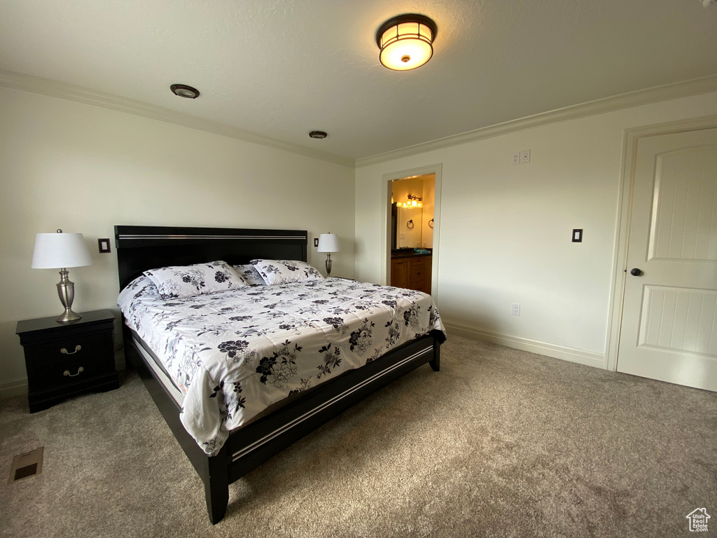 Bedroom with dark carpet, connected bathroom, and crown molding