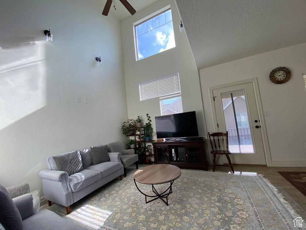 Tiled living room with a textured ceiling, ceiling fan, and a towering ceiling