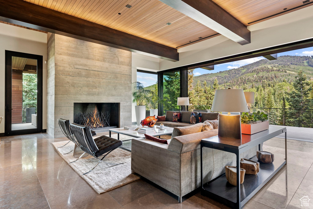 Living room featuring wood ceiling, a mountain view, a fireplace, and light tile flooring