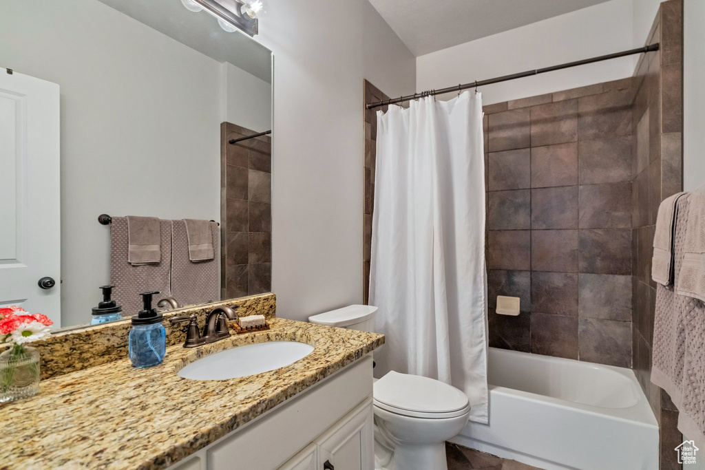Full bathroom with large vanity, toilet, and shower / tub combo with curtain
