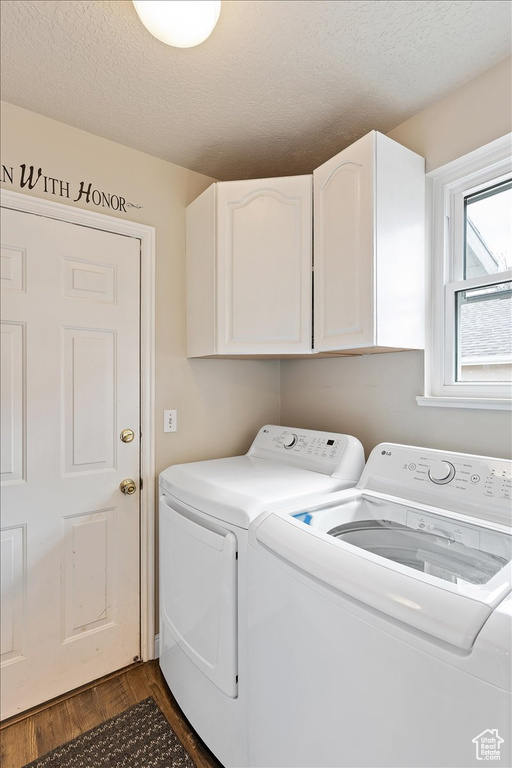 Clothes washing area featuring dark hardwood / wood-style floors, cabinets, a textured ceiling, and washer and dryer
