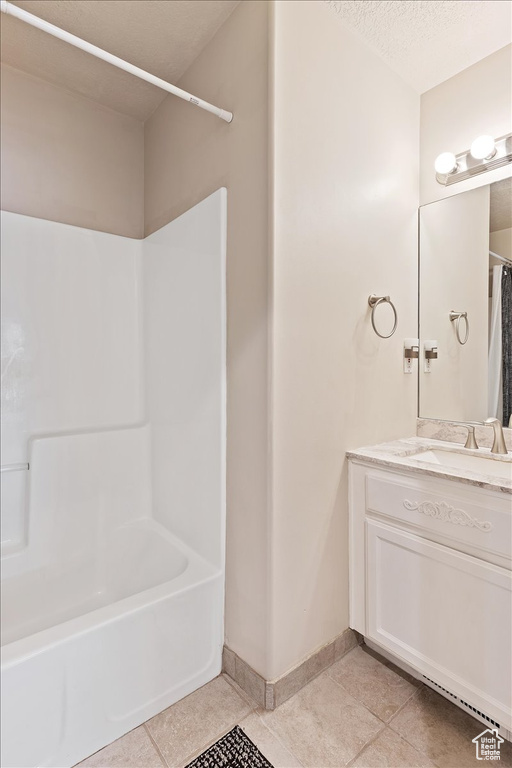 Bathroom with vanity, tile flooring, a textured ceiling, and shower / bathtub combination with curtain