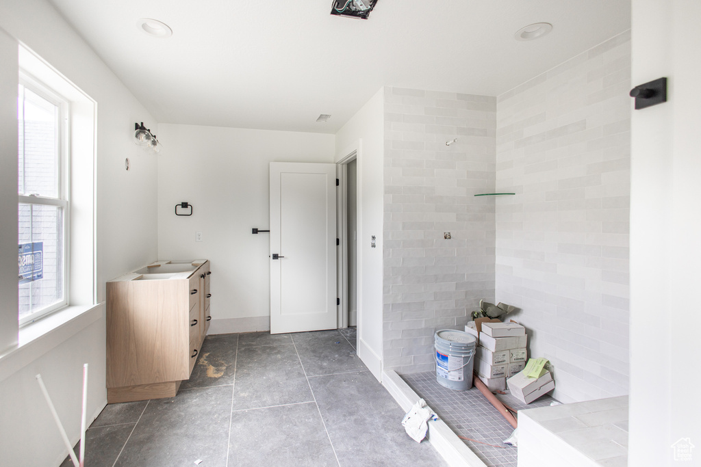 Bathroom featuring walk in shower, tile floors, and vanity