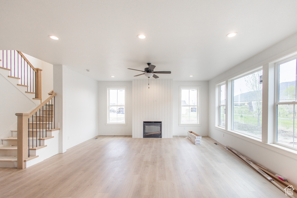 Unfurnished living room with a baseboard heating unit, light hardwood / wood-style floors, and ceiling fan