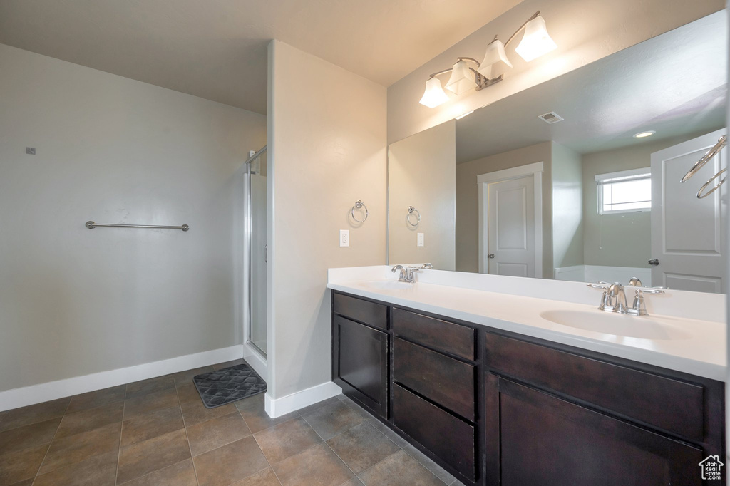Bathroom with an enclosed shower, double sink vanity, and tile flooring