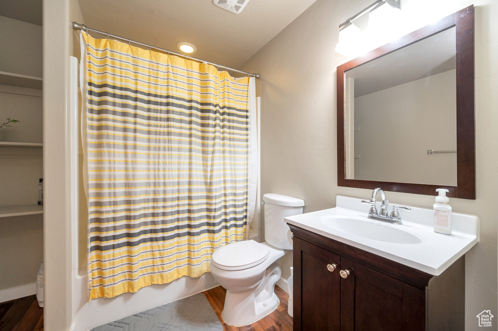 Full bathroom with oversized vanity, shower / bath combo, toilet, and wood-type flooring