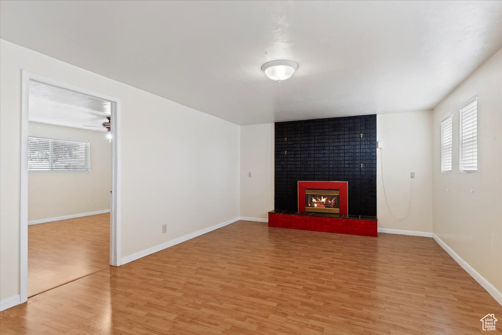 Unfurnished living room featuring ceiling fan, light wood-type flooring, and a fireplace