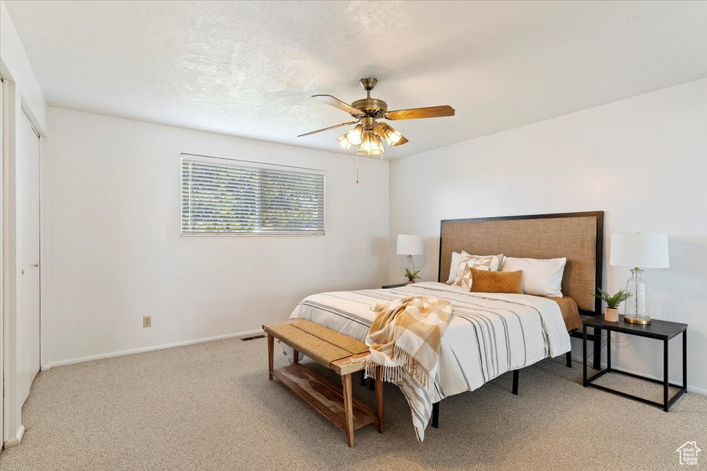 Carpeted bedroom with a textured ceiling, a closet, and ceiling fan