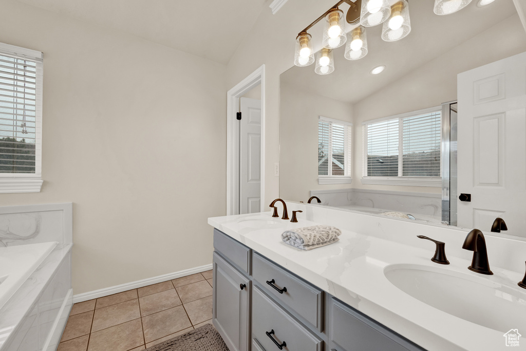 Bathroom with lofted ceiling, a notable chandelier, dual vanity, tile floors, and tiled tub