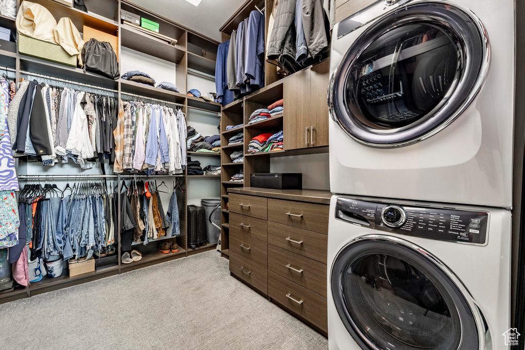 Interior space featuring stacked washer / dryer and light colored carpet