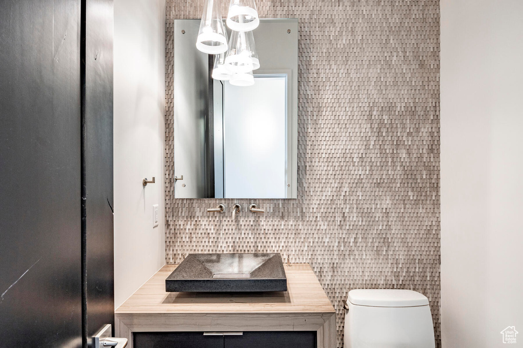 Bathroom featuring backsplash, tile walls, toilet, and vanity