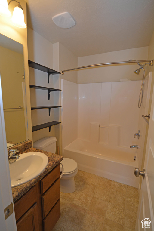 Full bathroom featuring toilet, tile floors, vanity, and shower / bath combination