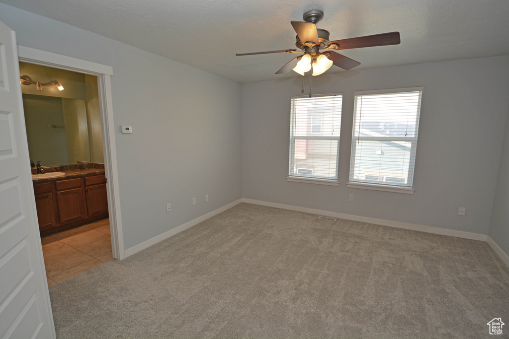Empty room with light carpet, ceiling fan, and sink