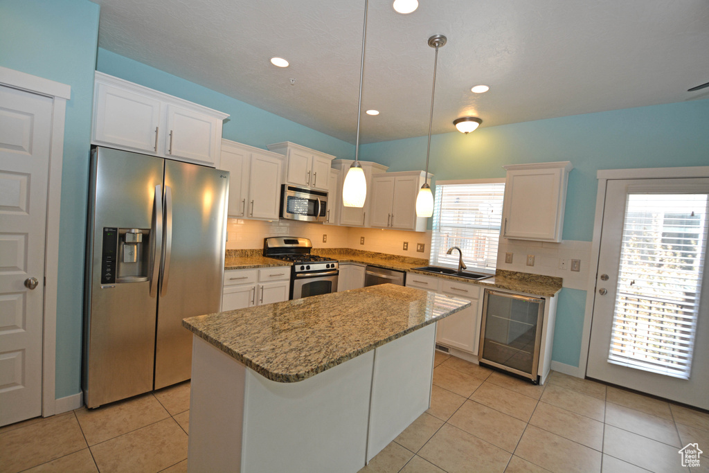 Kitchen with white cabinets, plenty of natural light, stainless steel appliances, and decorative light fixtures