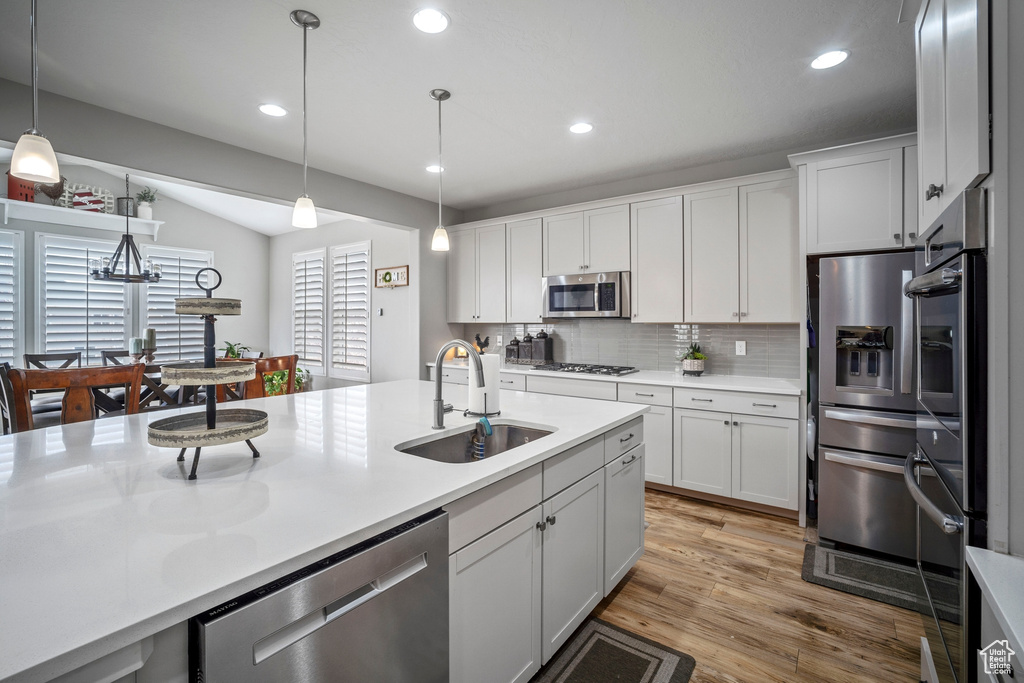 Kitchen with appliances with stainless steel finishes, tasteful backsplash, sink, and pendant lighting
