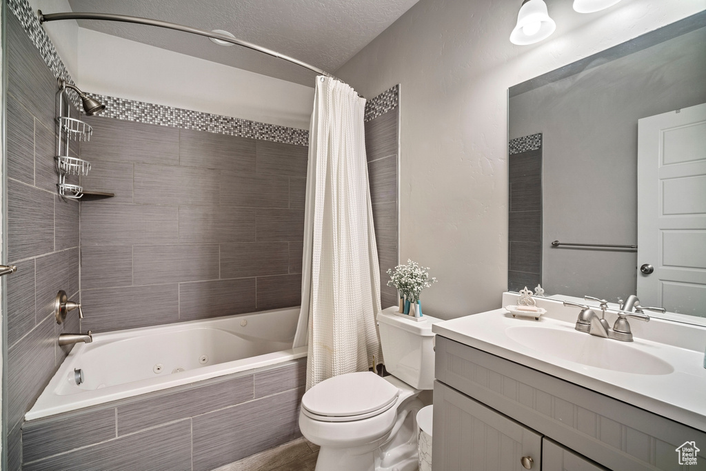 Full bathroom with toilet, oversized vanity, and shower / tub combo