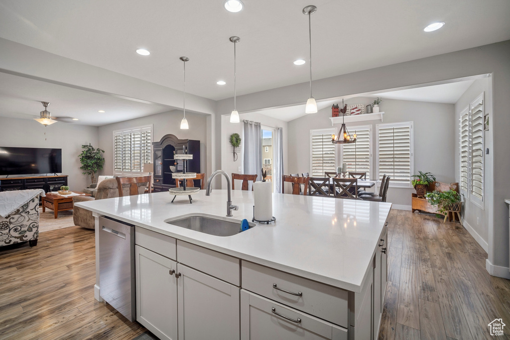 Kitchen featuring stainless steel dishwasher, ceiling fan, decorative light fixtures, dark hardwood / wood-style flooring, and sink