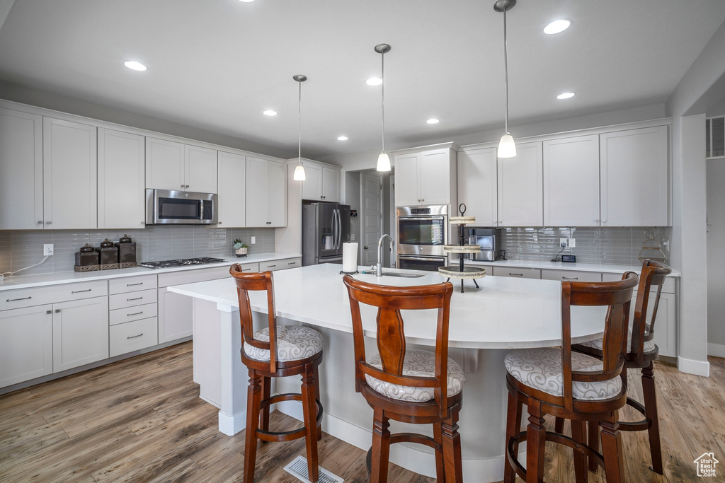 Kitchen featuring an island with sink, tasteful backsplash, stainless steel appliances, and a breakfast bar area