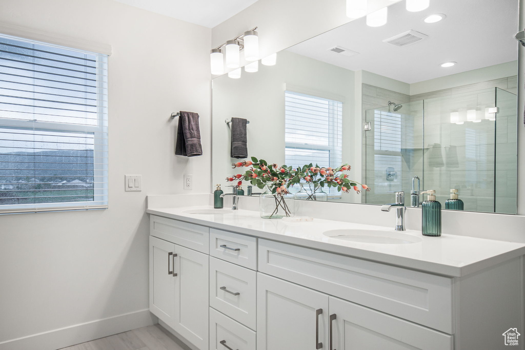 Bathroom featuring a wealth of natural light, dual vanity, and an enclosed shower