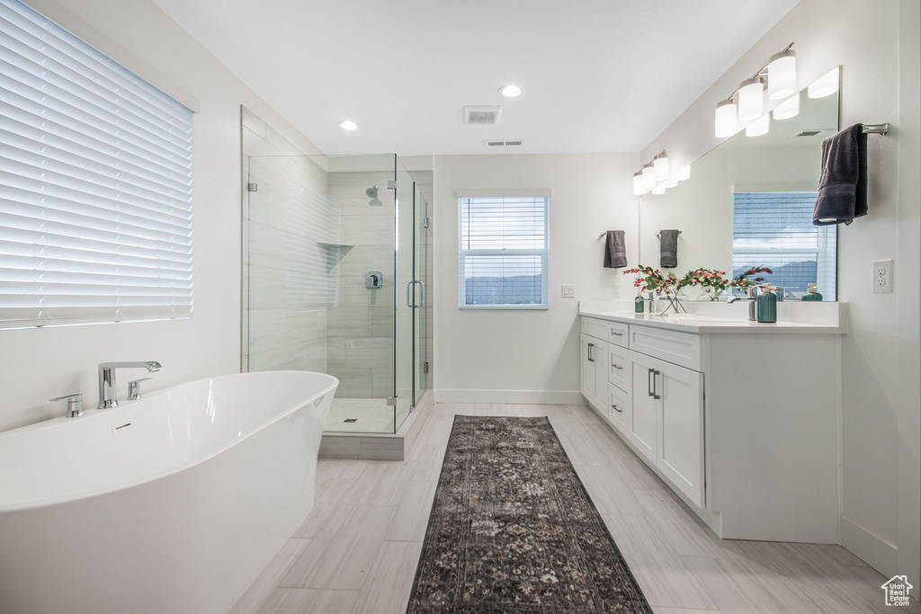 Bathroom with double sink vanity, tile flooring, and independent shower and bath