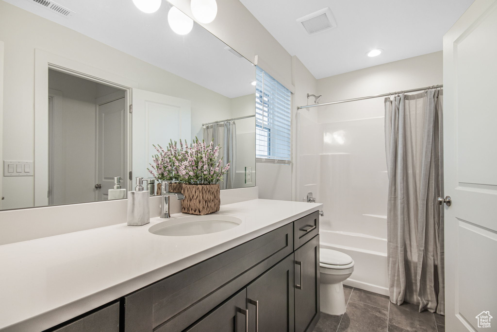Full bathroom featuring shower / tub combo, tile floors, oversized vanity, and toilet