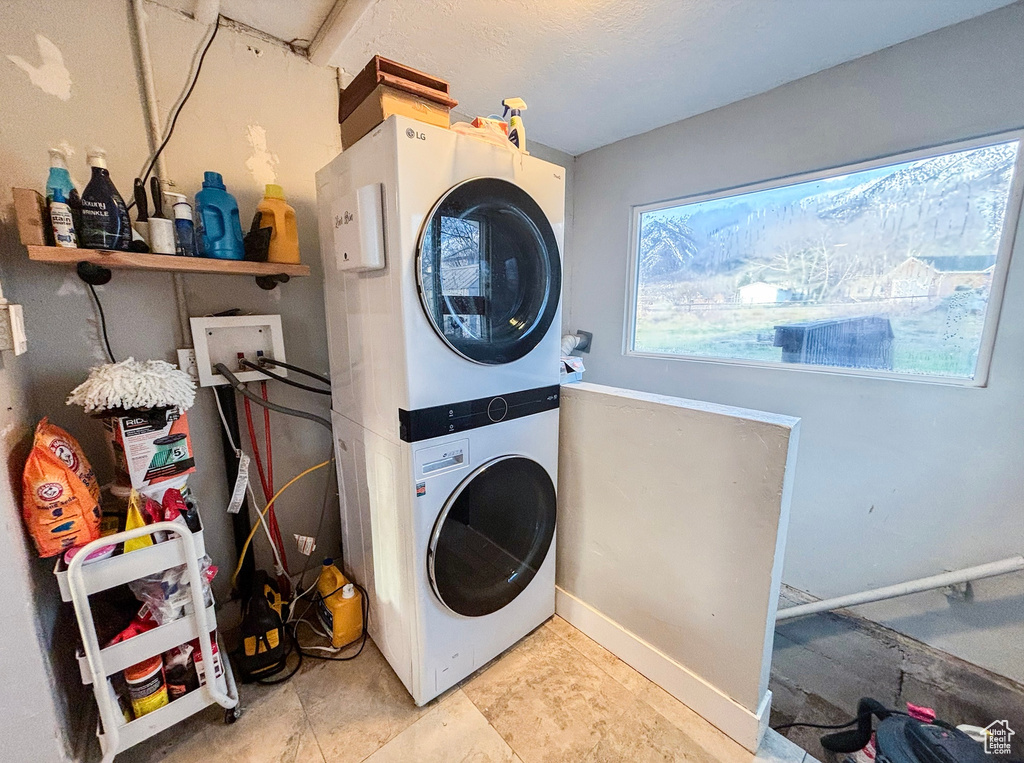 Clothes washing area featuring stacked washer and clothes dryer, light tile floors, and hookup for a washing machine