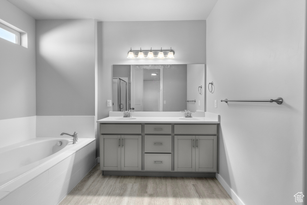 Bathroom with dual vanity, tiled tub, and hardwood / wood-style flooring