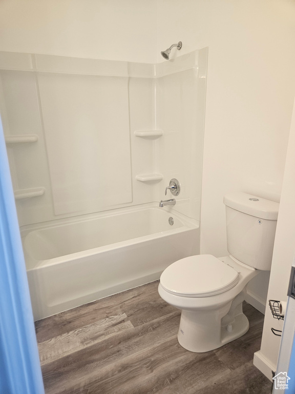Bathroom with toilet, bathtub / shower combination, and wood-type flooring
