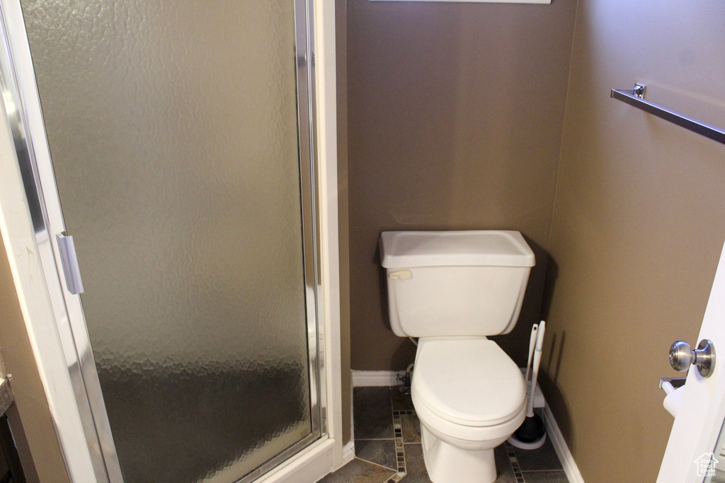 Bathroom featuring walk in shower, tile floors, and toilet