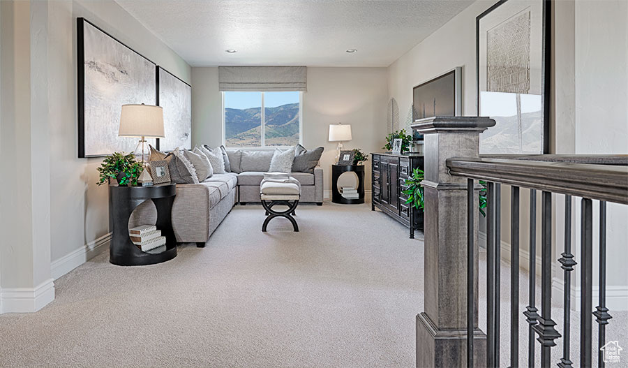 Living room featuring a textured ceiling, a mountain view, and light colored carpet