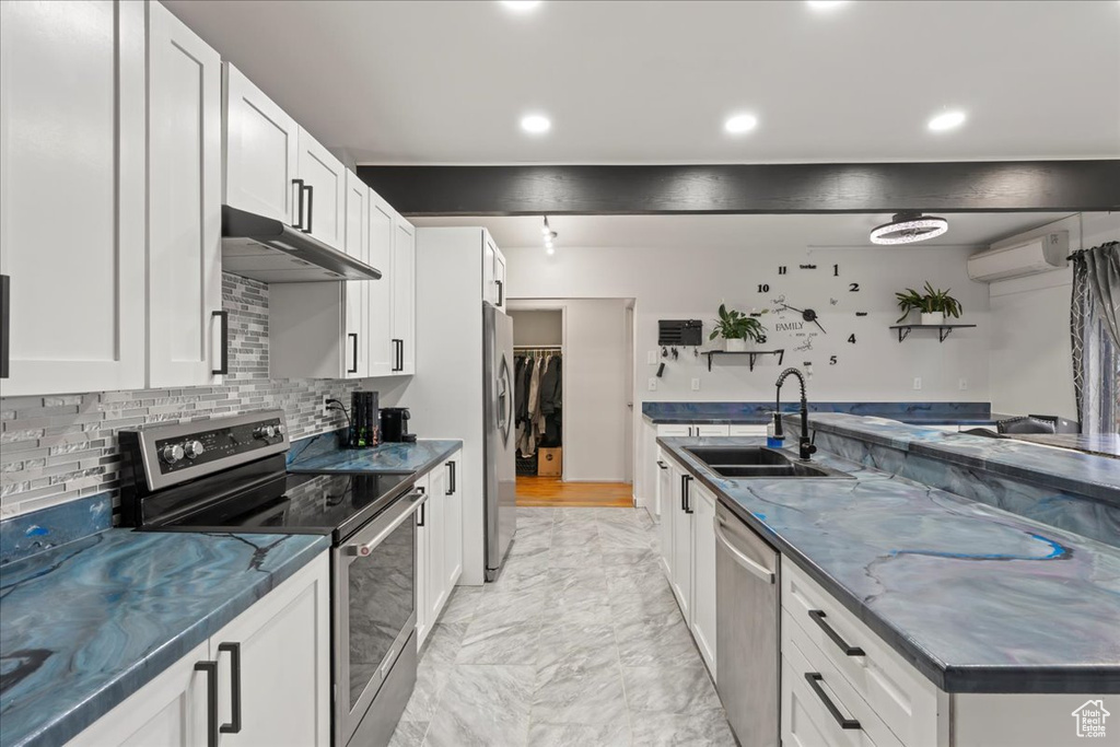 Kitchen featuring appliances with stainless steel finishes, white cabinetry, backsplash, and light tile flooring