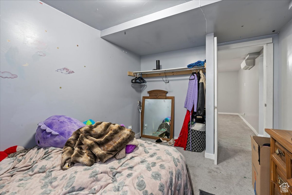 Bedroom with a wall mounted AC, light carpet, and a closet