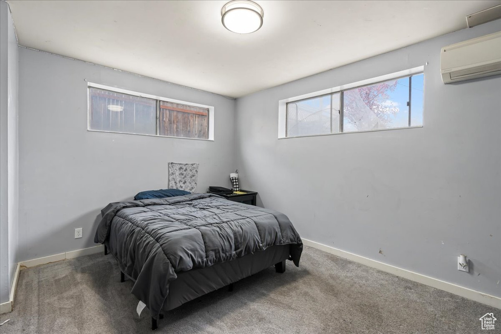 Bedroom featuring multiple windows, carpet, and a wall mounted AC