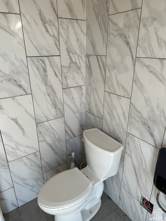 Bathroom with tile flooring, toilet, and tile walls