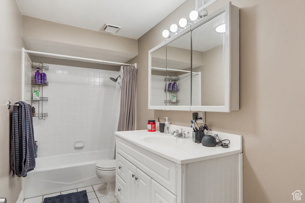 Full bathroom with toilet, tile floors, shower / bathtub combination with curtain, and large vanity