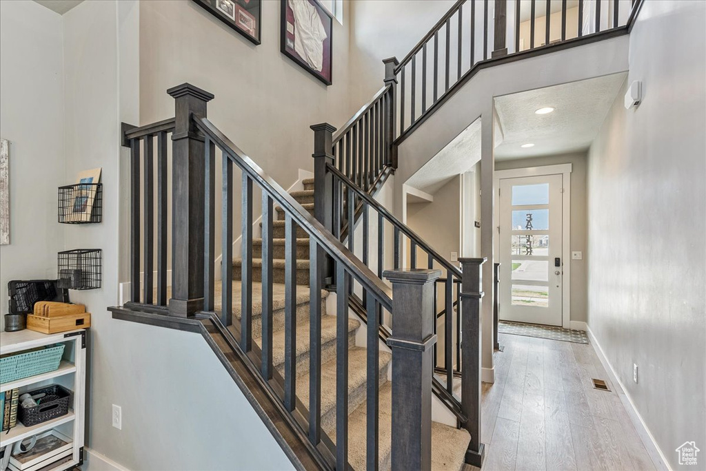 Stairs featuring a high ceiling and light hardwood / wood-style floors