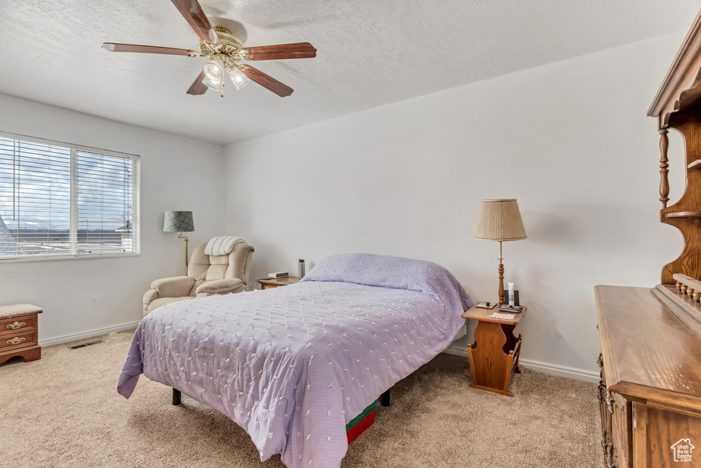 Carpeted bedroom with ceiling fan and a textured ceiling
