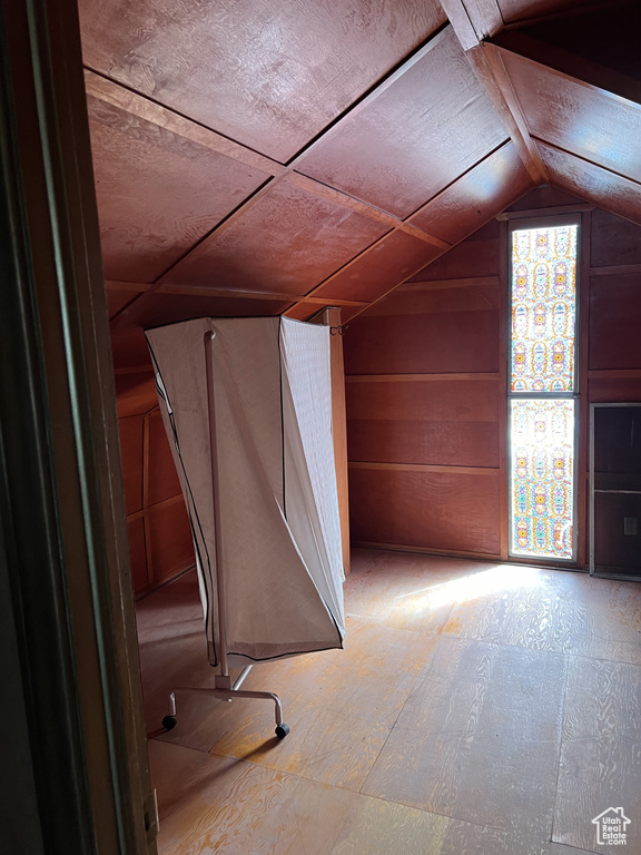 Bonus room featuring wood walls and lofted ceiling