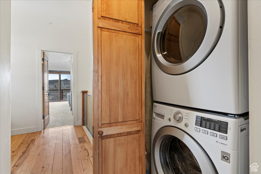 Laundry area featuring stacked washing maching and dryer and light hardwood / wood-style floors