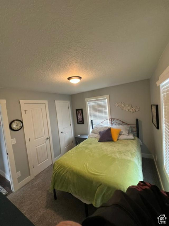 Bedroom with a textured ceiling and dark colored carpet