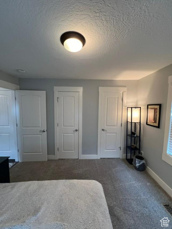 Unfurnished bedroom with carpet and a textured ceiling