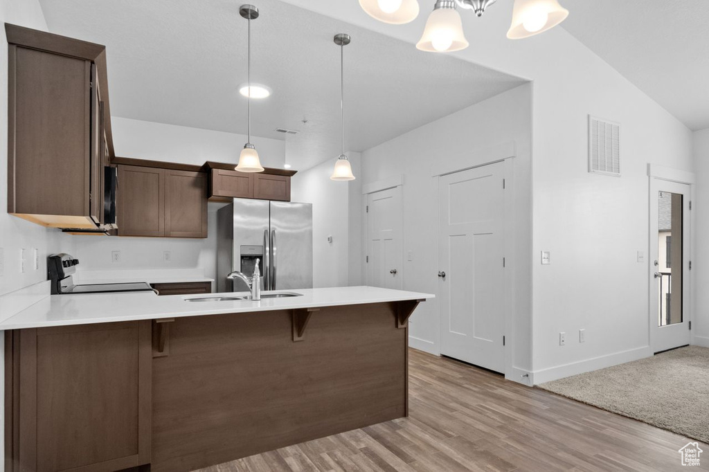 Kitchen featuring a chandelier, decorative light fixtures, stainless steel refrigerator with ice dispenser, range, and sink