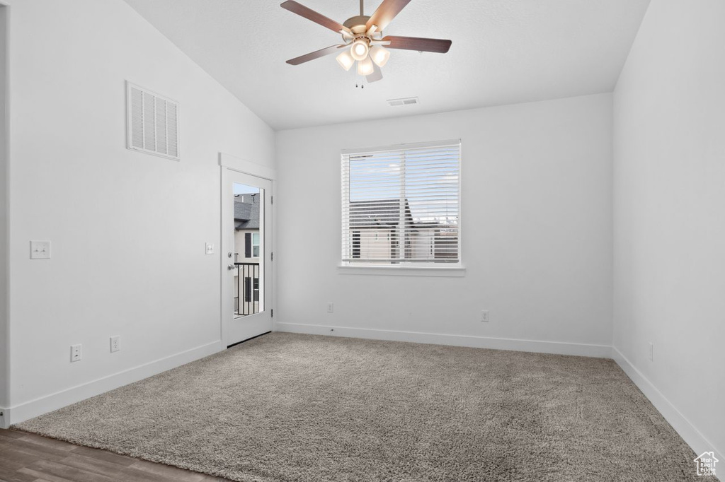 Empty room featuring vaulted ceiling, carpet flooring, and ceiling fan