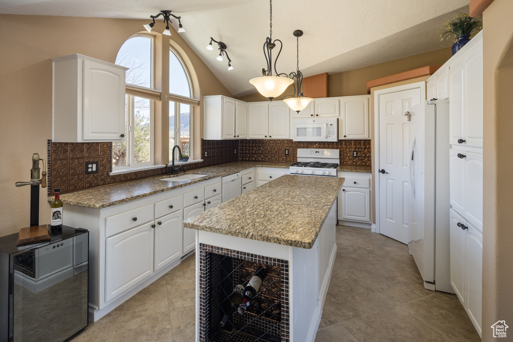 Kitchen featuring pendant lighting, a kitchen island, tasteful backsplash, white appliances, and sink
