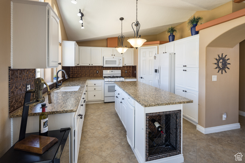 Kitchen with tasteful backsplash, sink, a center island, white appliances, and hanging light fixtures
